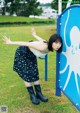 A young woman leaning against a blue and white sign.